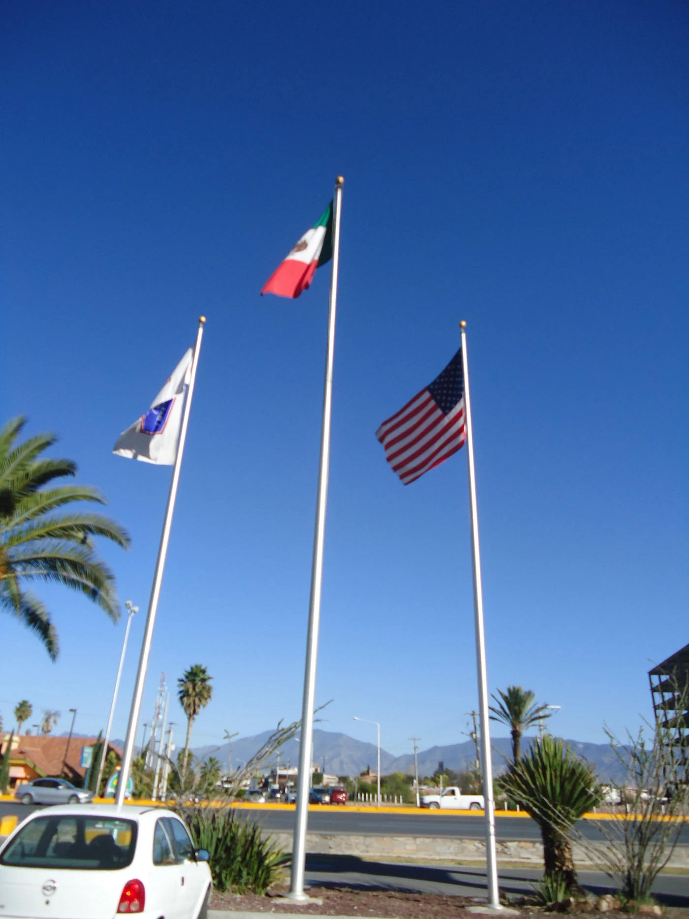 Astas con banderas de México, Estados Unidos y bandera institucional